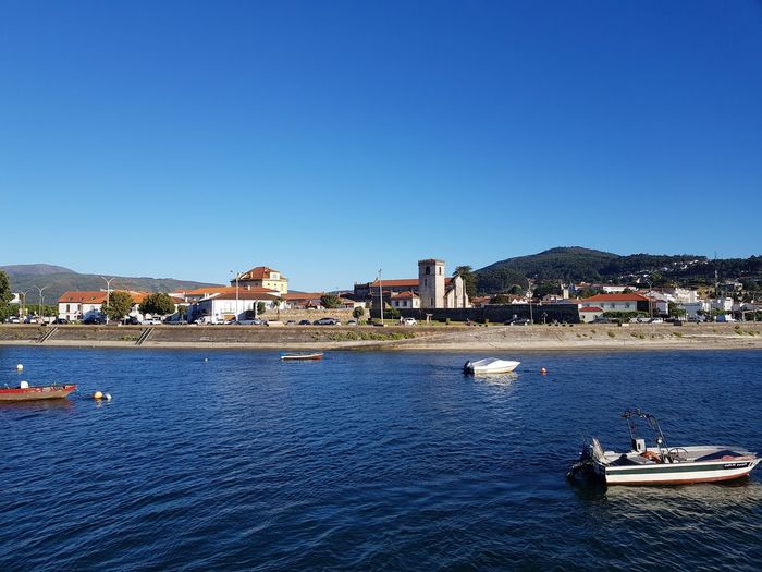 Scenic view of sea and buildings against clear blue sky