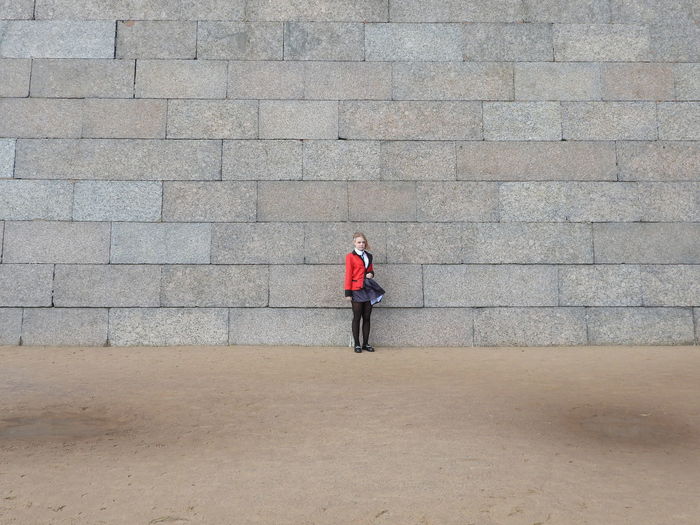 Full length of girl standing against wall