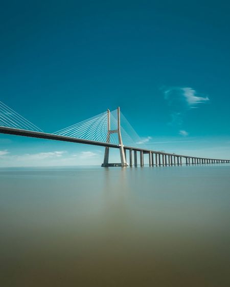 Suspension bridge over sea against sky