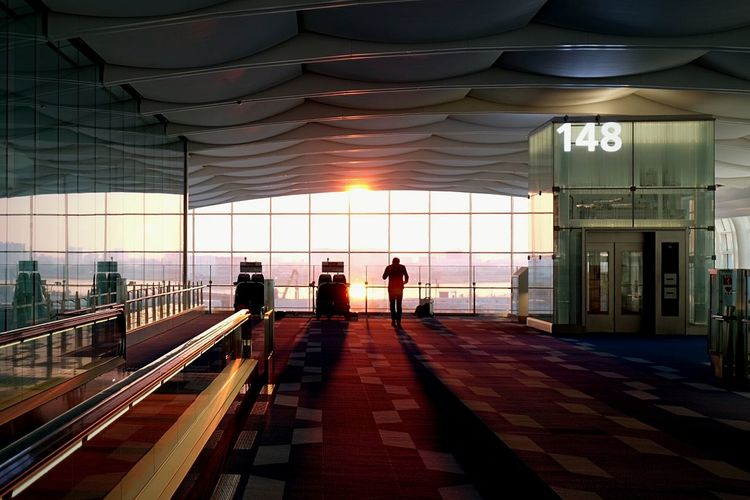 Silhouette man standing in departure area at airport during sunset
