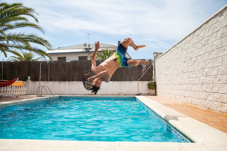Man jumping in swimming pool against sky