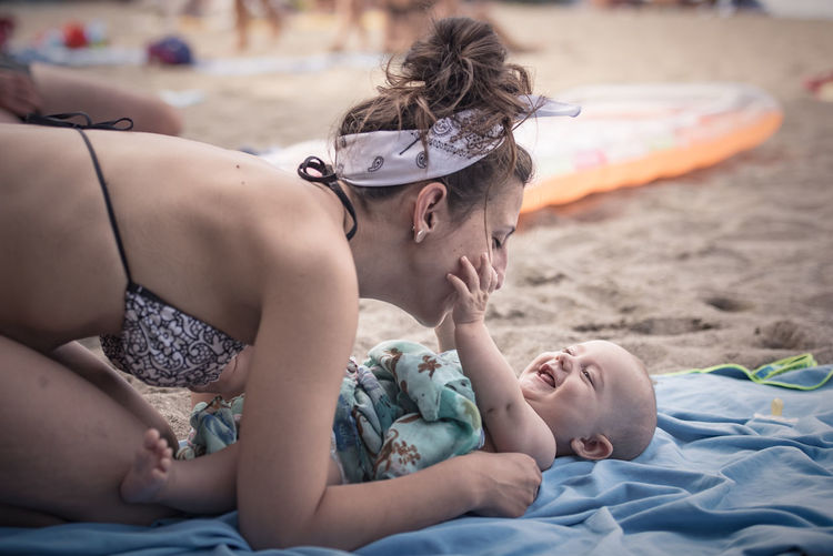 Side view of bikini woman with son playing at beach