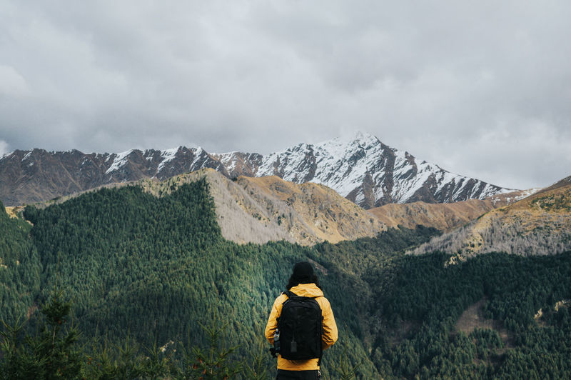 A man hiking on the top of mountain with snowcapped mountains view in the background.