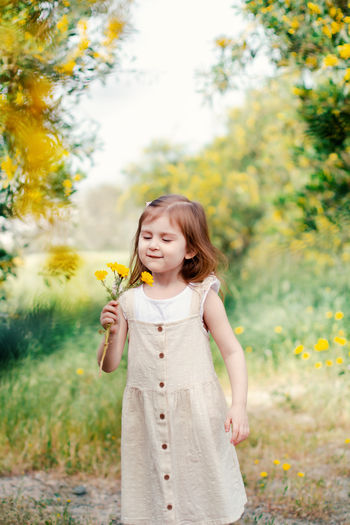 Young woman drinking water while standing against trees