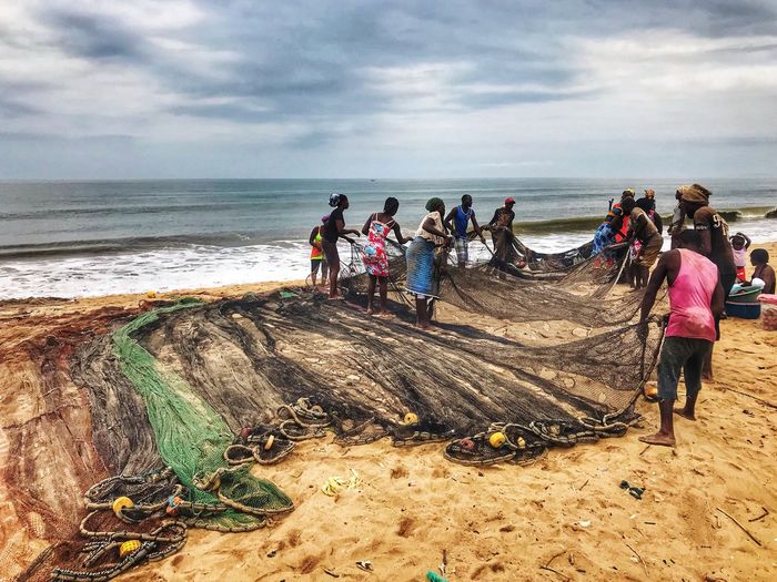 People on beach separating fishing nets at shore of beach