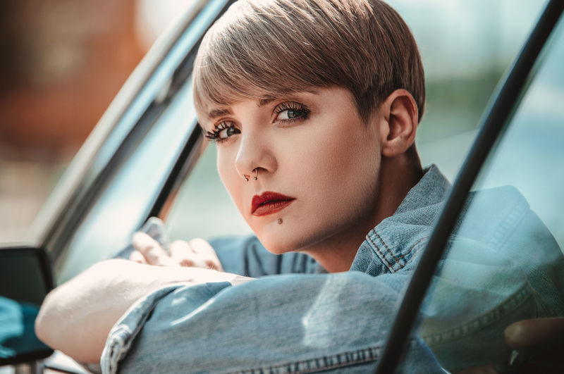 Portrait of woman with short hair looking through car window