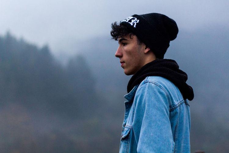 Side view of handsome young man wearing knit hat during foggy weather