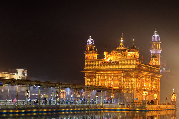 Illuminated buildings in city at night, golden temple amritsar 