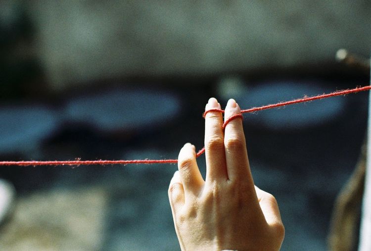 Cropped image of woman hand holding wool string on sunny day