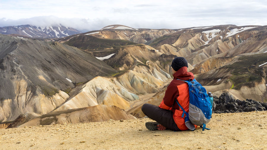 Male hiker taking a break looking at landmannalaugar sandy hills