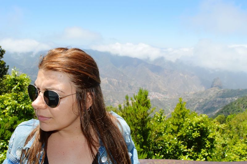Close-up of young woman wearing sunglasses while standing against mountains