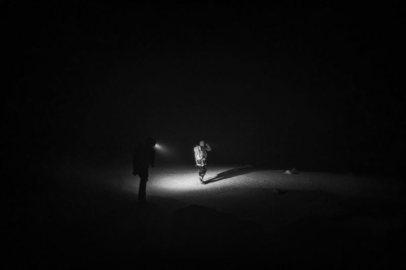 Two alpine climbers walk in the dark on the summit of mt. katahdin