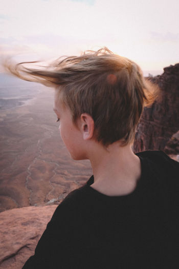 Wind blowing boy's hair over canyonlands viewpoint.