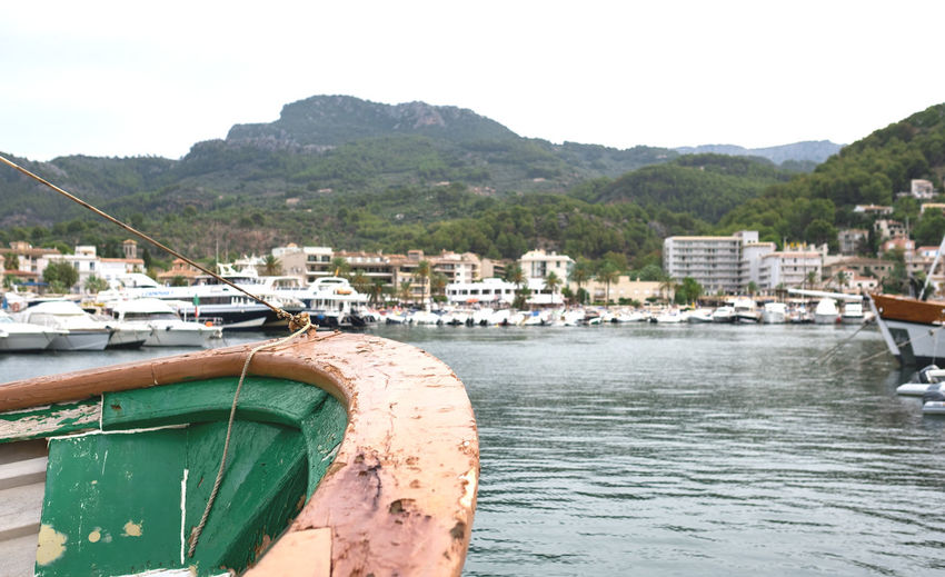 Close-up of boat anchored at river by buildings and mountains