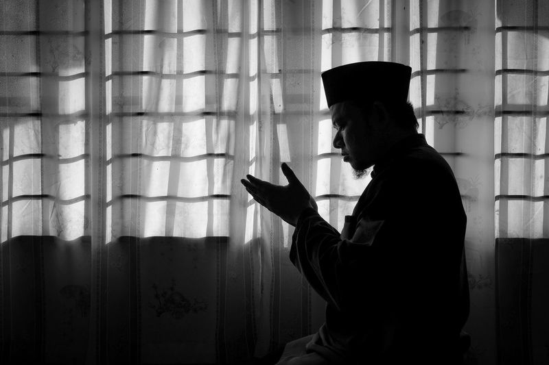 Side view of an praying in darkroom