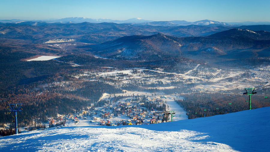 View of a small village sheregesh, high mountains and coniferous forest from a high point in winter 