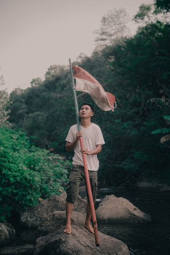 A young man is lifting the red and white flag of the indonesian nationality
