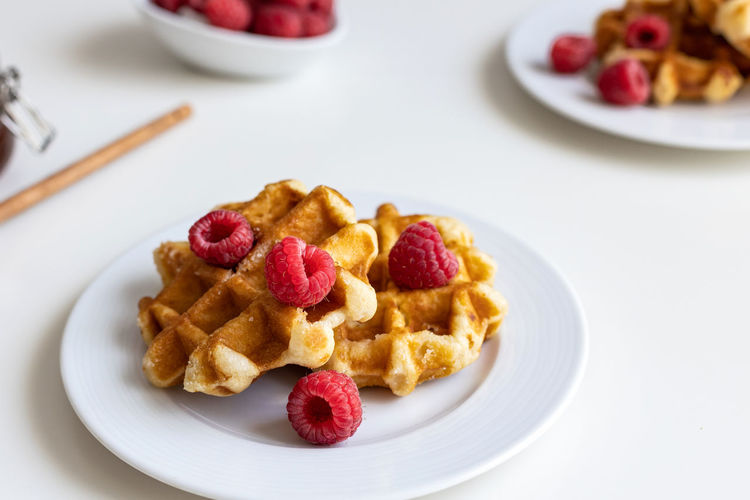 Homemade, fresh belgian waffles lie on a plate with fresh berries. lovely breakfast