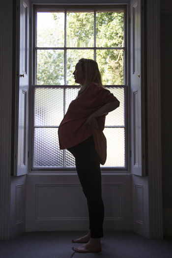 Woman standing by window at home