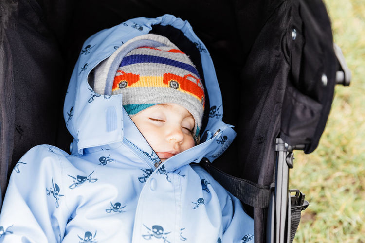 Close-up of baby girl sleeping in stroller on field