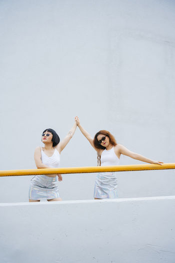 Lesbian couple holding hands while standing by railing outdoors