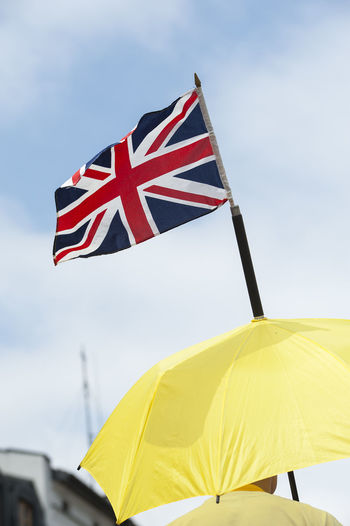 Close-up of british flag on yellow umbrella against sky