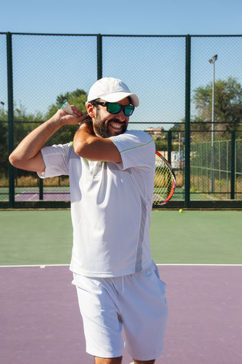 Smiling man playing tennis in court