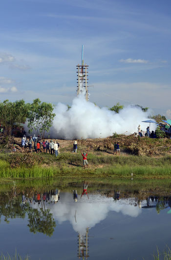 Group of people watching rocket launch on landscape