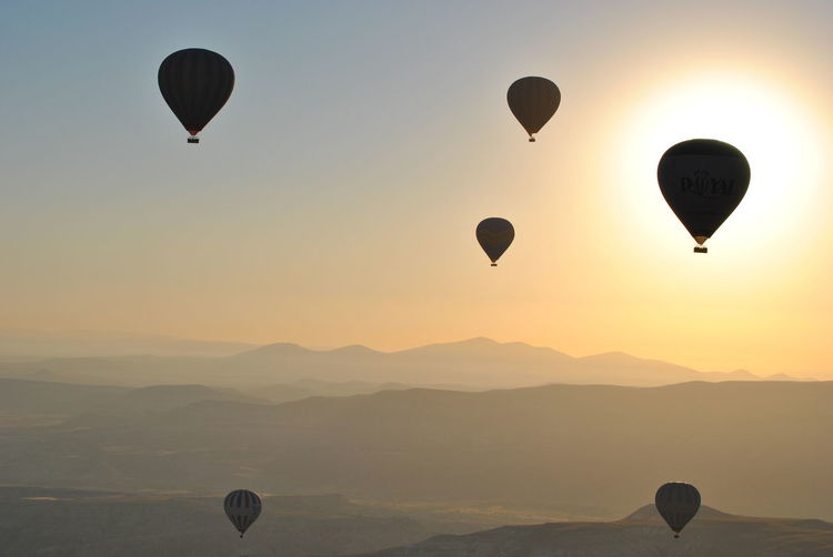 Hot air balloons flying against sky during sunset