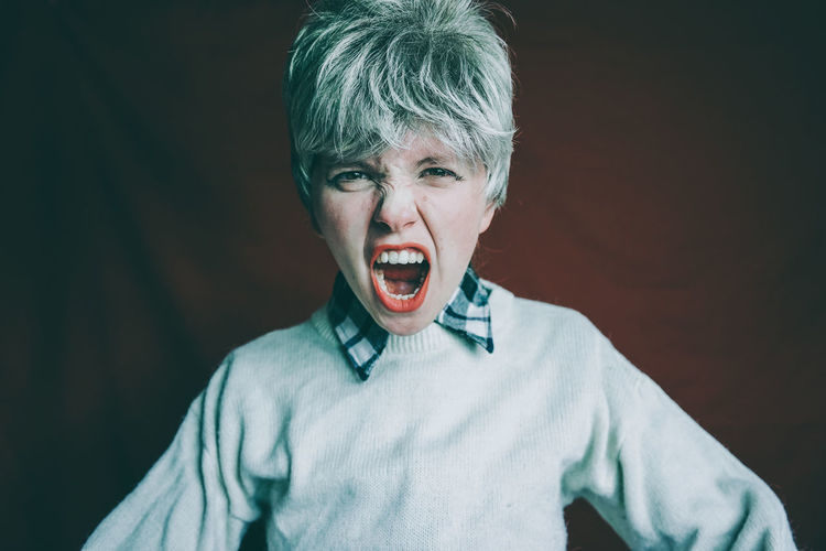 Portrait of screaming woman against black background