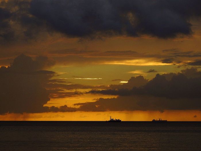 Scenic view of sea against dramatic sky during sunset