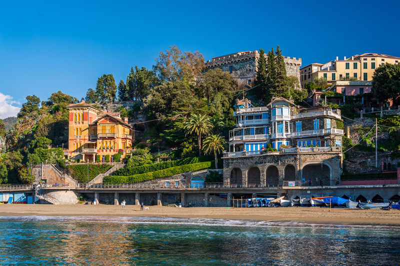 Buildings by river against clear blue sky