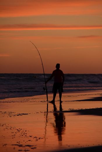 Silhouette man fishing in sea
