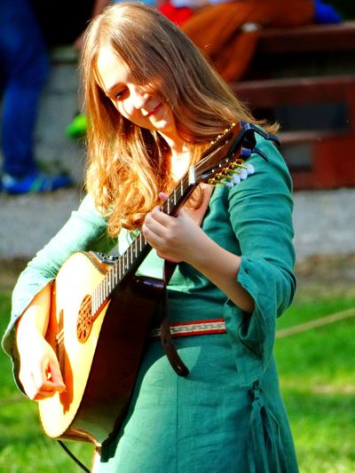 Woman playing mandolin while standing on field