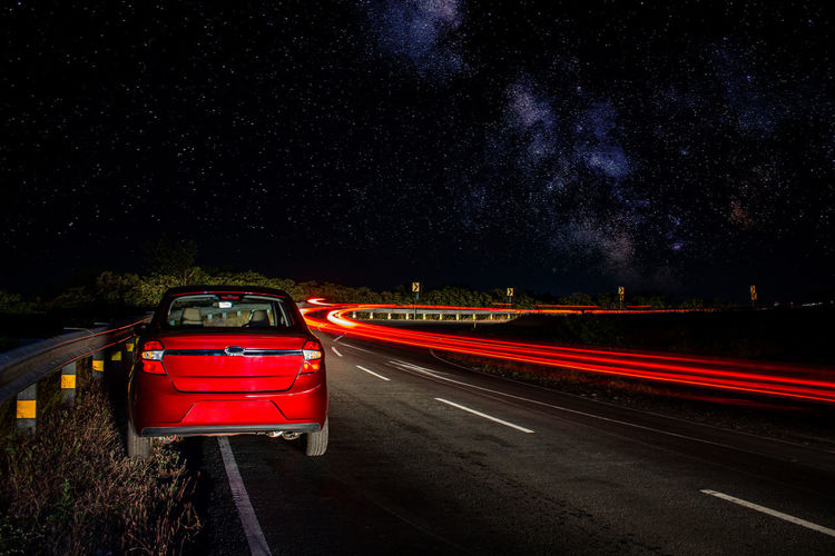 Light trails on road against sky at night