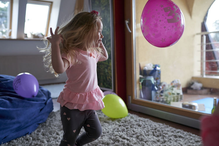 Girl playing with balloons at home