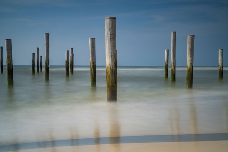Long exposure seascape.  with the pole village in the sea, blue sky, . focus on foreground.
