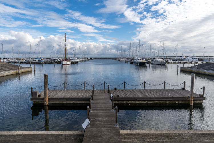 Sailboats moored in sea against sky