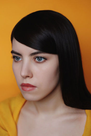 Close-up portrait of a beautiful young woman over yellow background