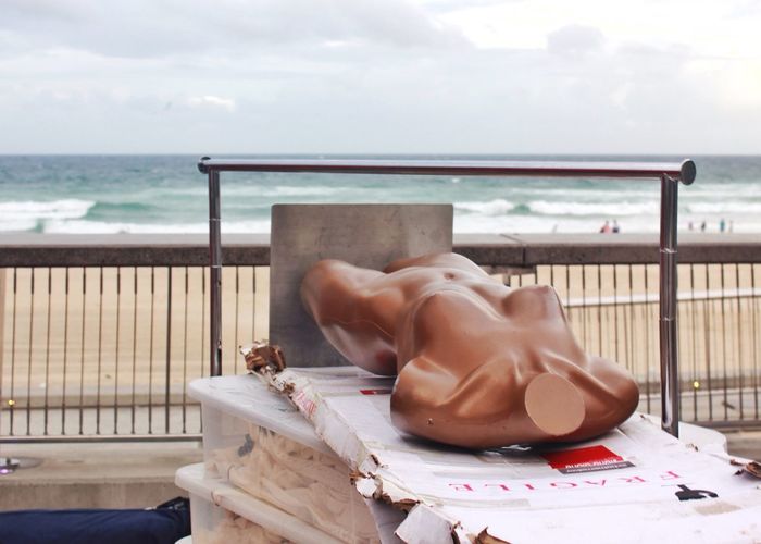 Abandoned mannequin on cardboard at beach against sky