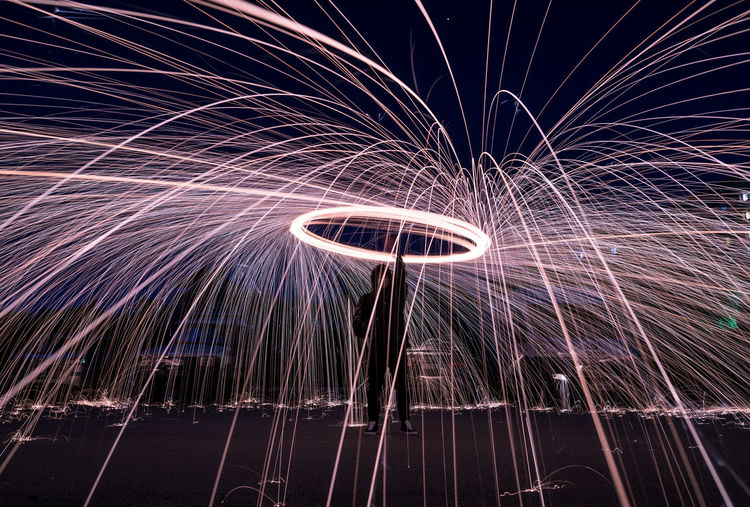 Man spinning wire wool against sky at night