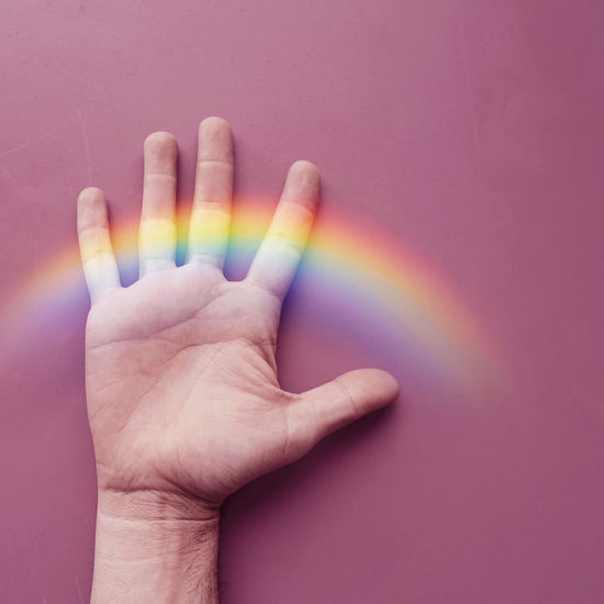 Hand with a rainbow on the pink wall. lgbt symbol