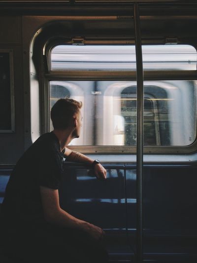 Man looking through window while traveling in train