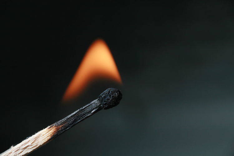 Close-up of burning match on black background