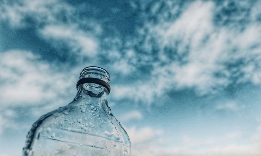 Low angle view of glass bottle against sky
