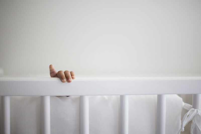 Close-up of hand holding railing on crib