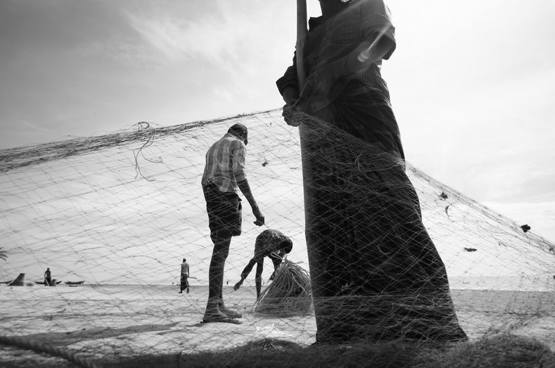 Low section of fisherman holding fishing net at beach