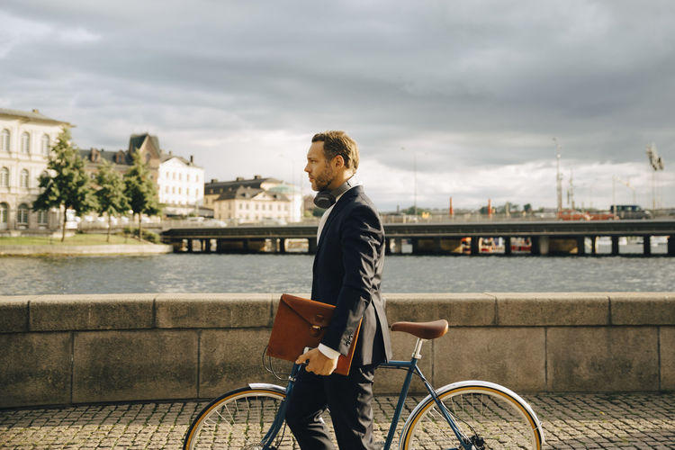 MAN RIDING BICYCLE ON RIVERBANK IN CITY
