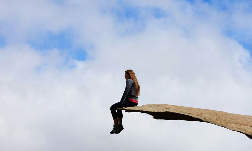 Low angle view of woman sitting at potato chip rock against sky