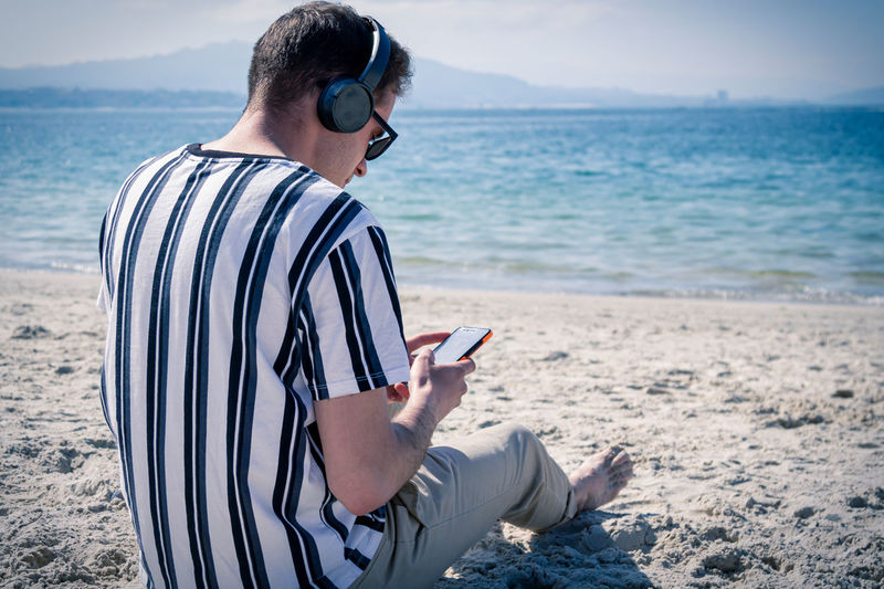 Relaxed man on the beach listening to music with his headphones
